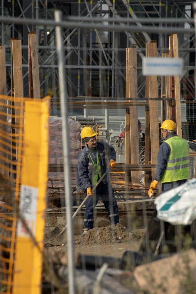 service-1 Construction workers in hard hats at an active building site with safety barriers.