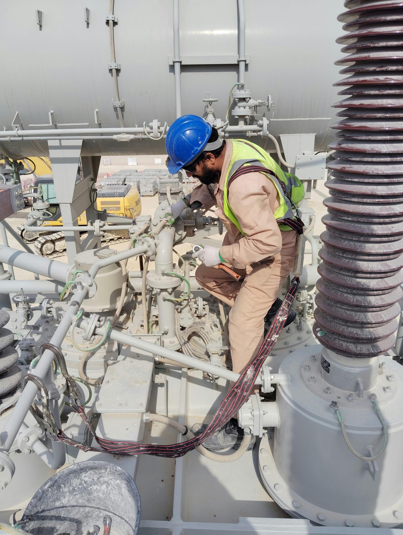 service-1 Engineer in safety gear inspecting equipment on a busy industrial construction site.
